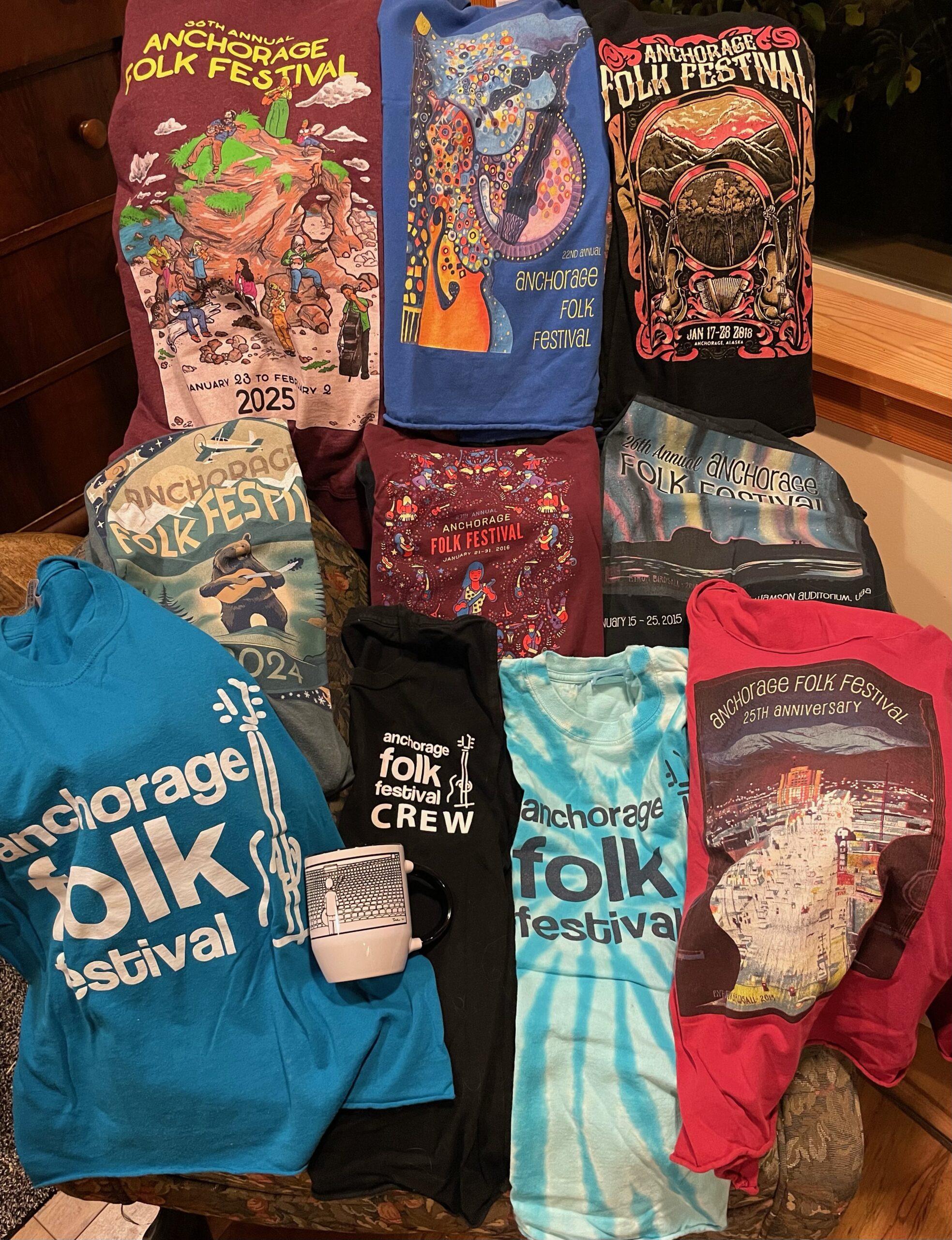 photograph of apparel and mug bearing past Anchorage Folk Festival official artwork